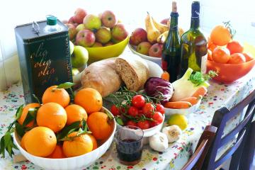 A table of food, all components of a Mediterranean diet, such as fruits and wine.