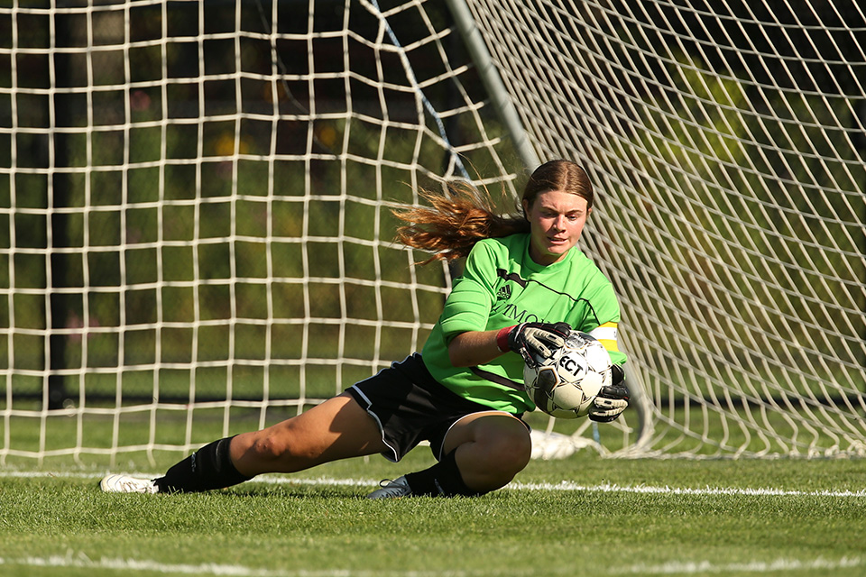 Goalie, Briana Hayes saving goal on soccer field.