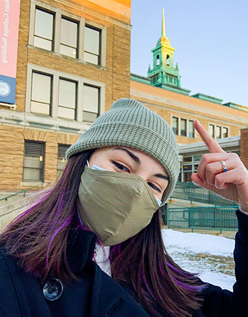 Bella Yee on the academic quad pointing to the Cupola