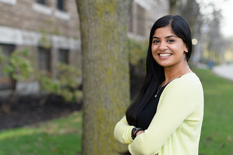 Student smiling by tree on campus
