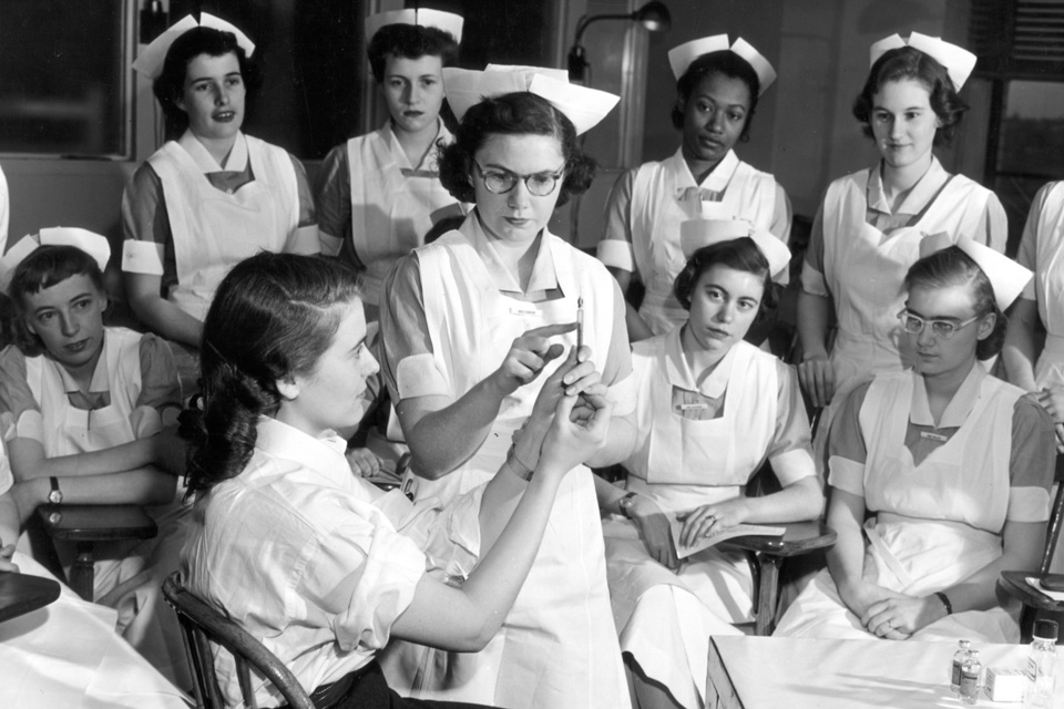 Unidentified nursing students posed observing instructions on using hypodermic needles.