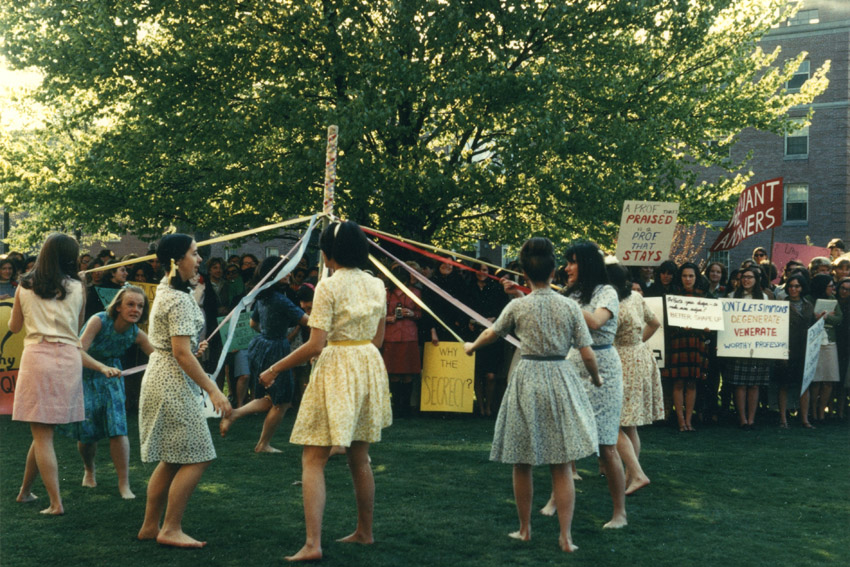 Students dance around the Maypole as protestors look on in 1967, courtesy of Simmons University Archives