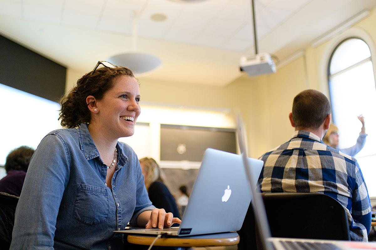 A Simmons graduate student in a classroom with an open laptop on the desk