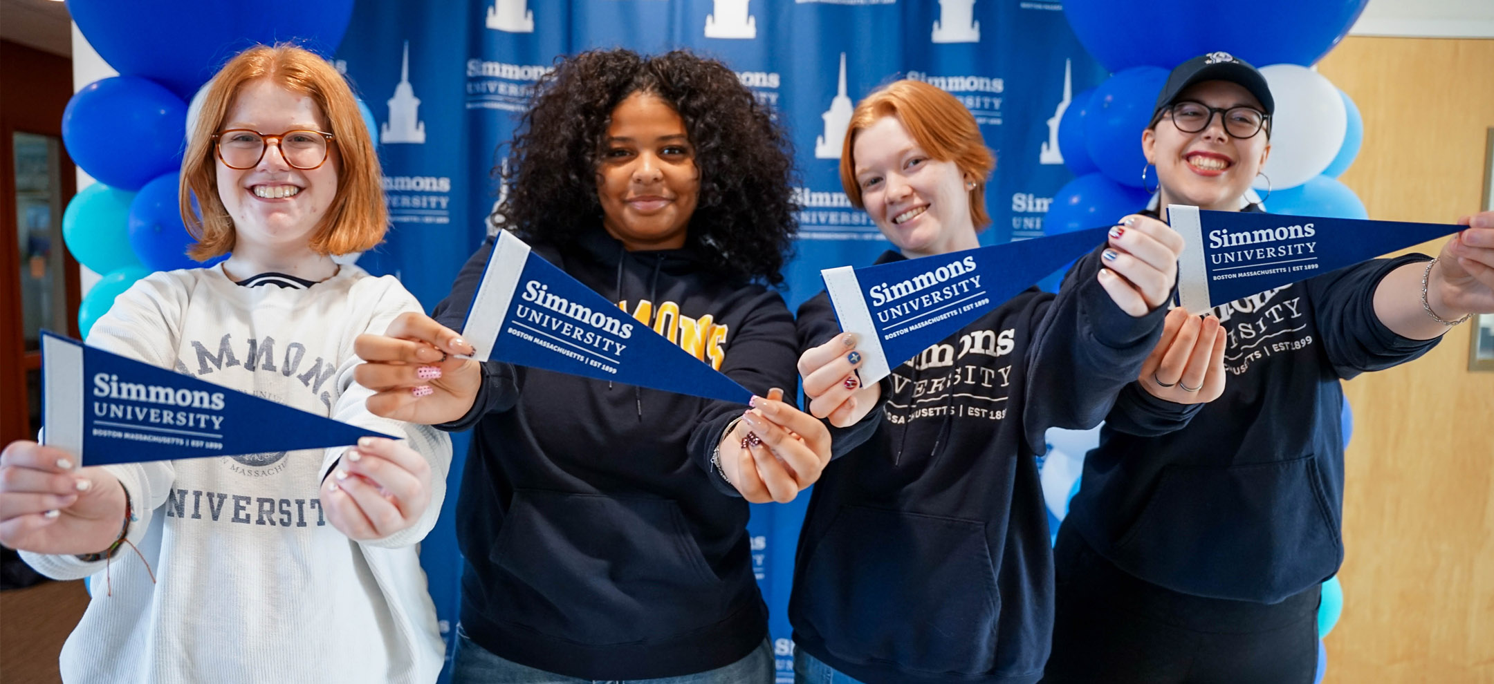 Happy students holding Simmons pennants