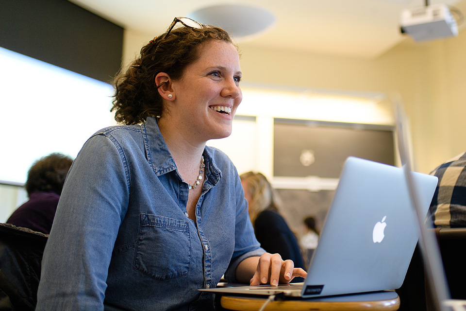 A Simmons graduate student in a classroom with an open laptop on the desk