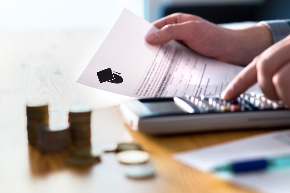 A person using a calculator while holding student loan papers