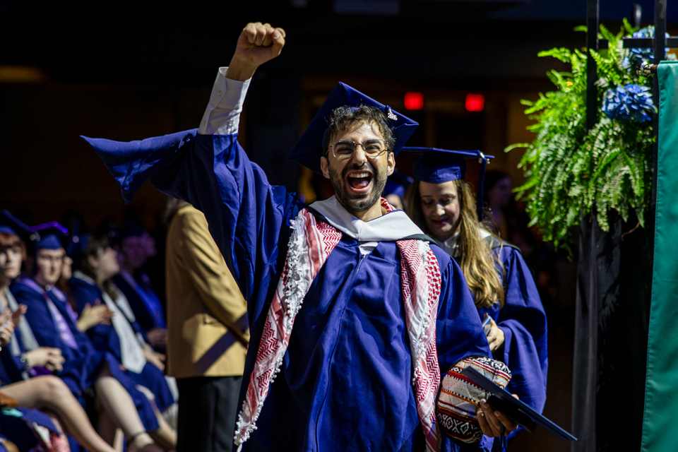 A graduate student pumping his fist in the air at Commencement 2026