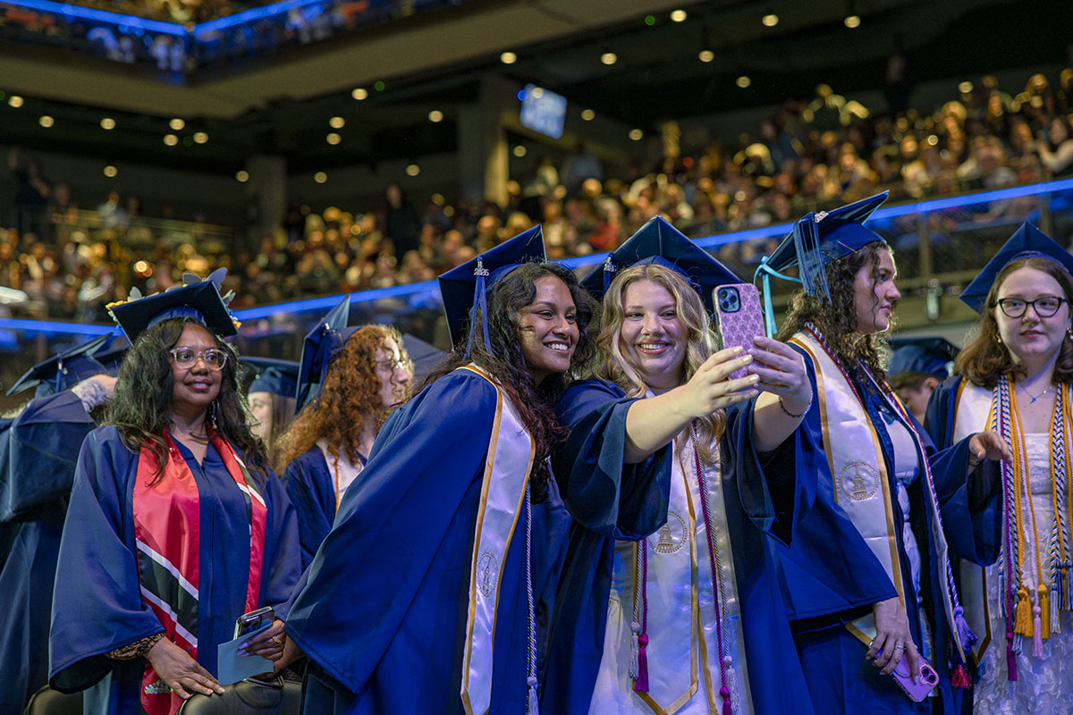 Two students taking a selfie during the 2026 Commencement ceremony for Simmons University 