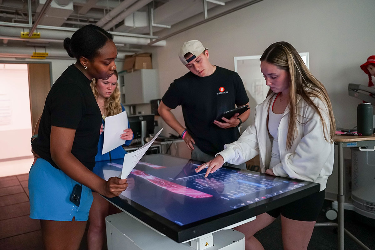 Four Simmons physical therapy students working at an anatomage table