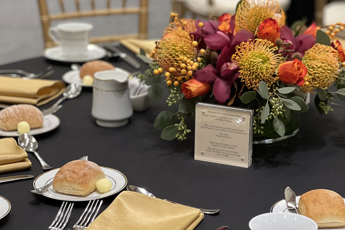 A table set for a dinner event, with a colorful fall centerpiece