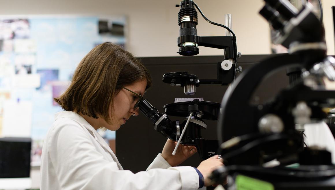 Student looking into a microscope in a lab