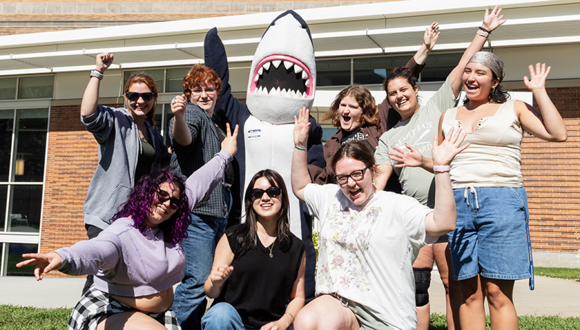 A group of orientation leaders and Stormy waving with excitement 