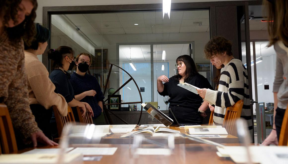 A group of Simmons students around a table covered with archival materials