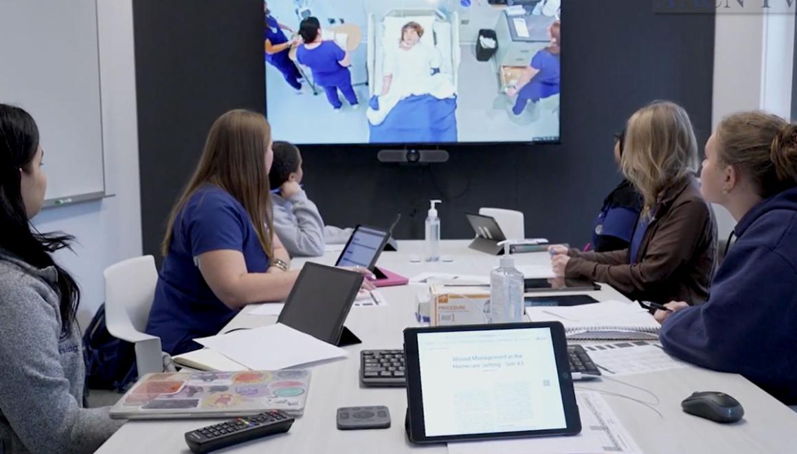A group of students observing a simulation lab training on a monitor