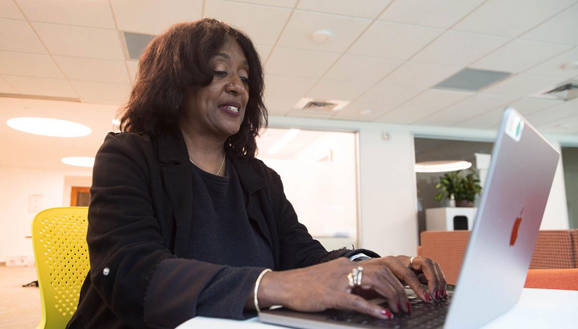 An adult Simmons student working on a laptop