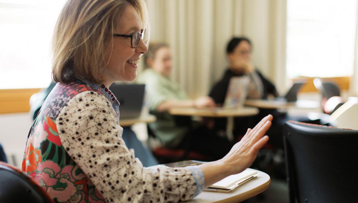An adult Simmons students smiling and gesturing during a class