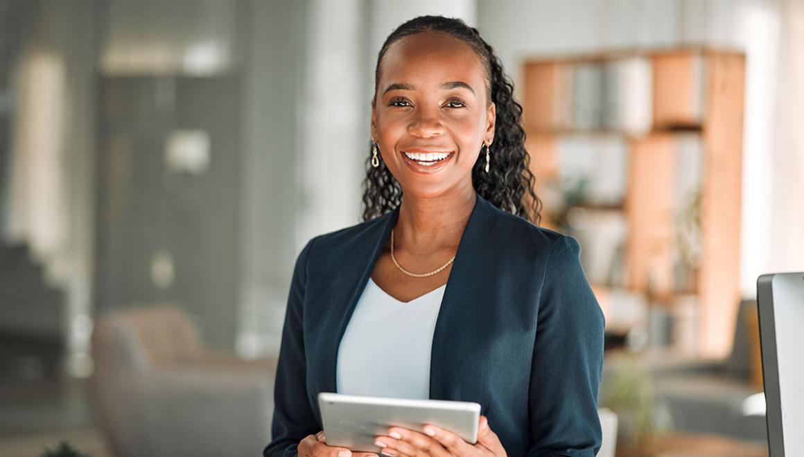 A young woman wearing a green blazer and holding a tablet 