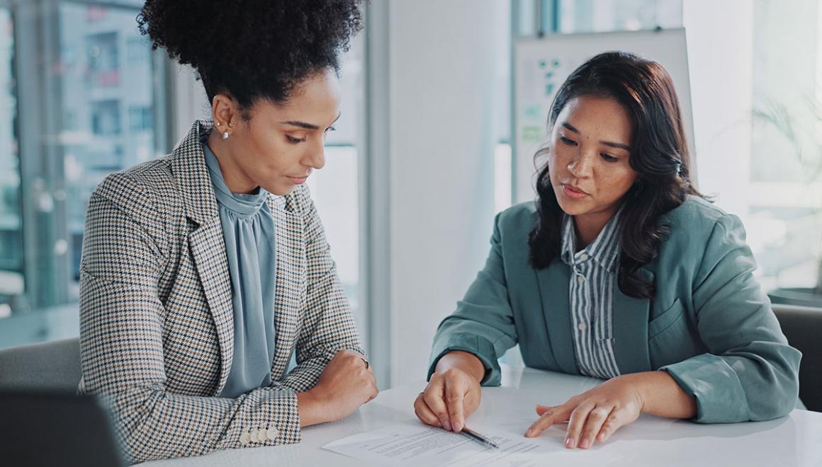Two women seated at a desk reviewing a paper