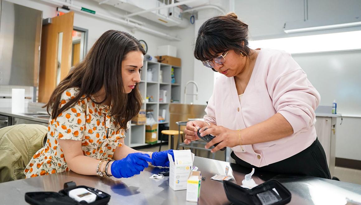 A graduate student in the nutrition lab learning how to administer a blood sugar test