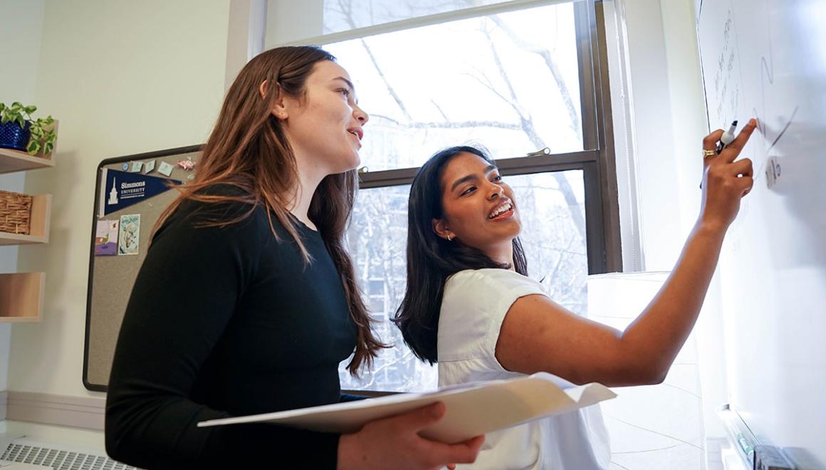 Two Simmons graduate students working together at a white board