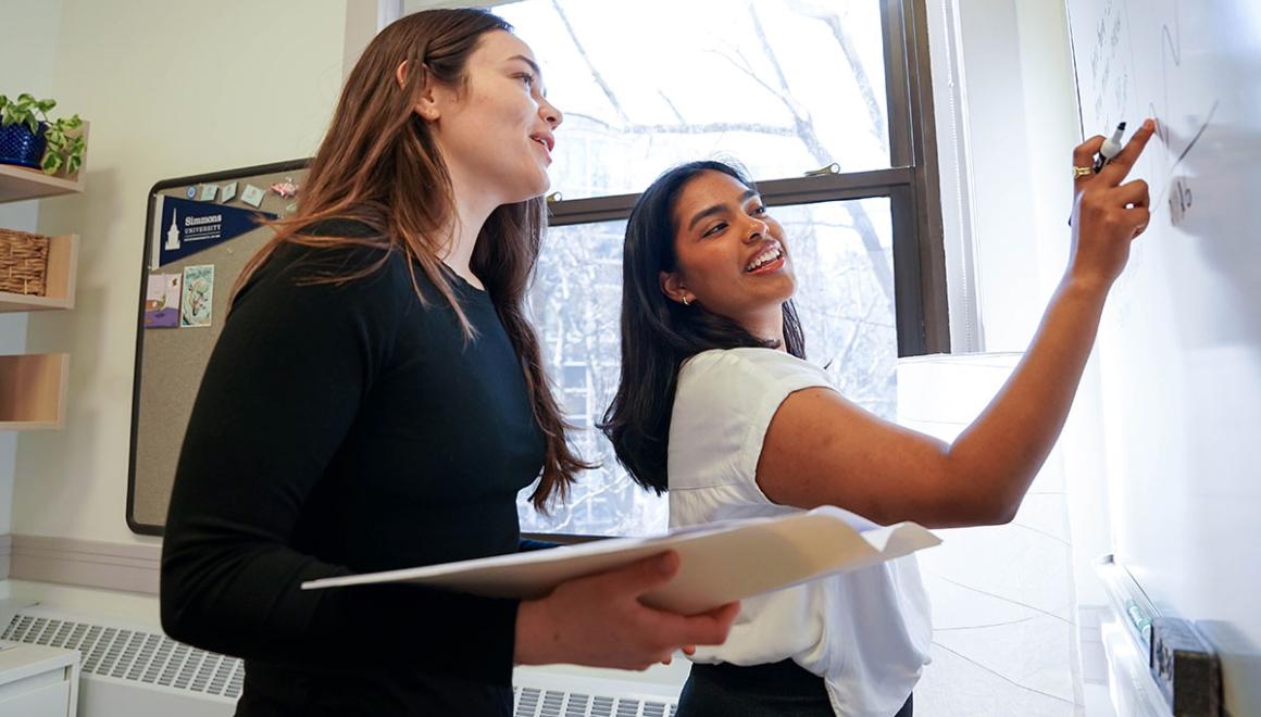 Two Simmons graduate students working together at a white board