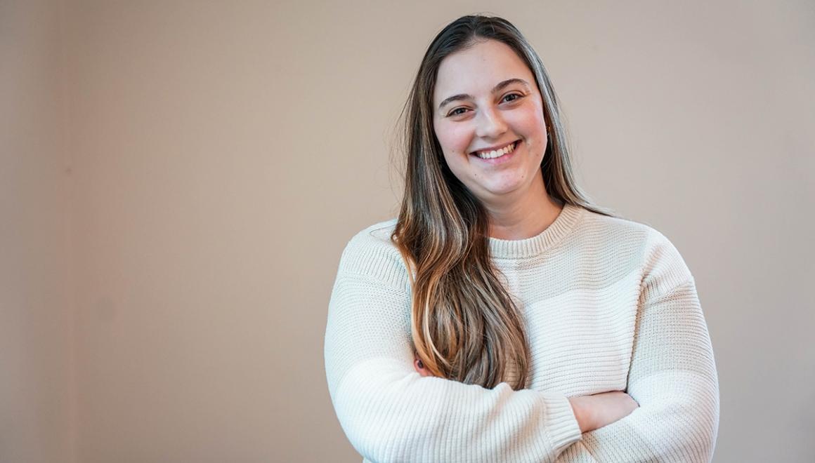Student posing with arms crossed, smiling.