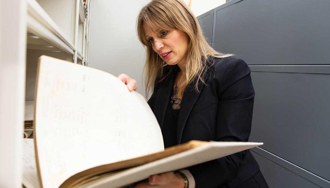 A graduate student studying an archival document in a library stack
