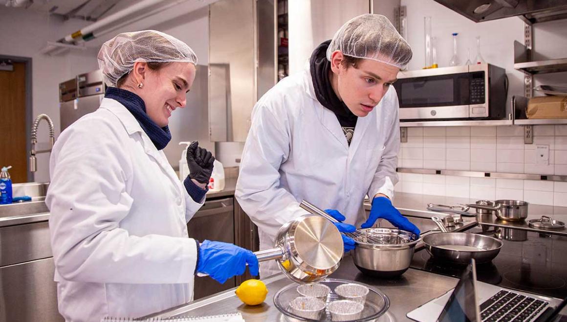 Two Simmons nutrition students in the nutrition lab doing an experiment involving cheese