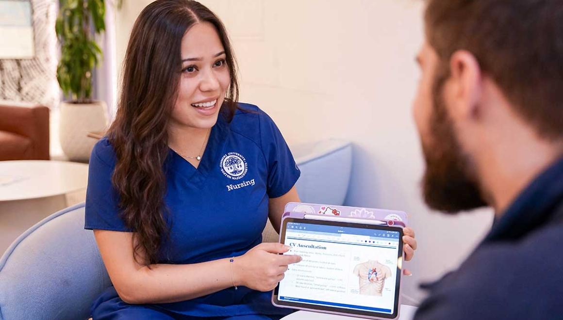 Two Simmons graduate nursing students sharing a tablet with an image of human anatomy on the screen