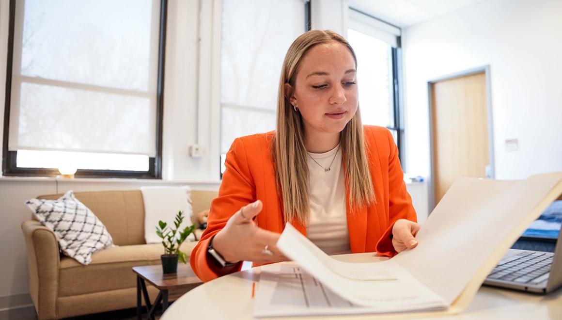 A Simmons management student looking over materials on a table.