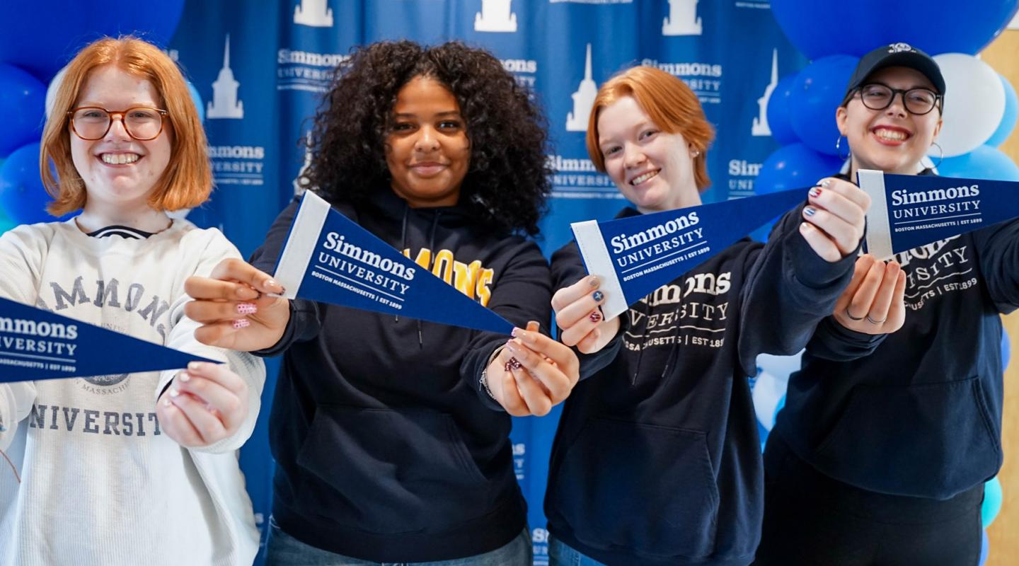 Happy students holding Simmons pennants