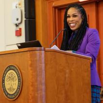 Dr. Uche Blackstock at the podium during the 2025 Community Read event at Simmons University