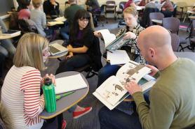 Students sitting in class looking at picture books