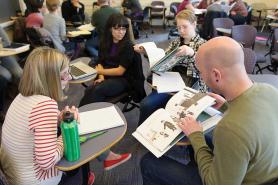 Students sitting in class looking at picture books