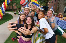 A group of Simmons students taking a selfie during an outdoor celebration.