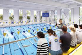 A rendering of students both in the pool and on the bleachers in the pool area of the new Living and Learning Center