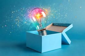 A lightulb popping out of a gift box surrounded by confetti