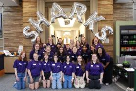 A group of 2025 orientation leaders posing in front of balloons that spell out SHARKS