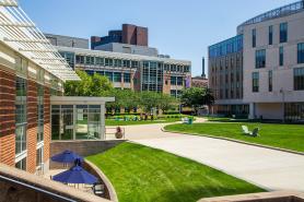 Photo of main campus quad on a bright sunny day. the view is looking from the Fens towards Drinan Hall and Palace Road