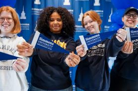 Happy students holding Simmons pennants