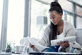 A young woman with paperwork in one hand and a notebook in the other