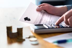 A person using a calculator while holding student loan papers