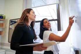 Two Simmons graduate students working together at a white board