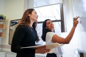 Two Simmons graduate students working together at a white board