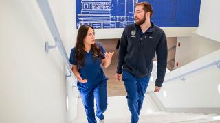Two Simmons graduate nursing students talking as they climb a set of stairs
