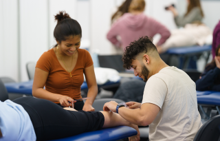 Two graduate students doing hands-on training in the Physical Therapy lab