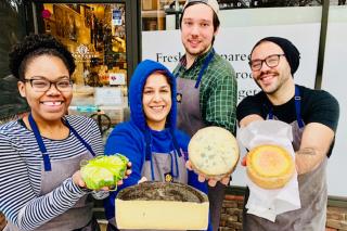 Hannah Morrow holding cheeses with her coworkers.