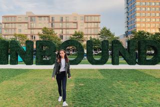 Lauren Kaye standing in front of hedges spelling out "INBOUND"