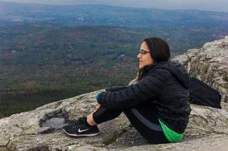 Saloni Kumar sitting on top of a mountain.