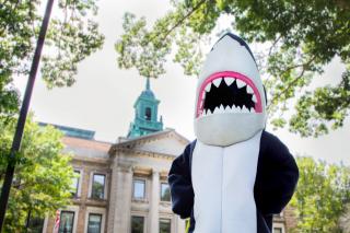 Stormy Shark standing outside the Simmons MCB with Cupola in the distance